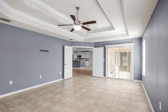 spare room featuring a tray ceiling, ceiling fan, light tile patterned floors, and ornamental molding