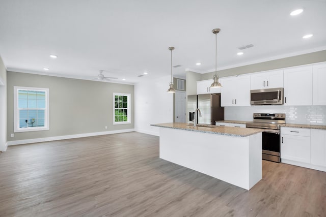 kitchen featuring white cabinetry, an island with sink, sink, hanging light fixtures, and stainless steel appliances