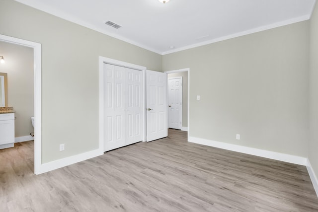 unfurnished bedroom with ornamental molding, a closet, and light wood-type flooring