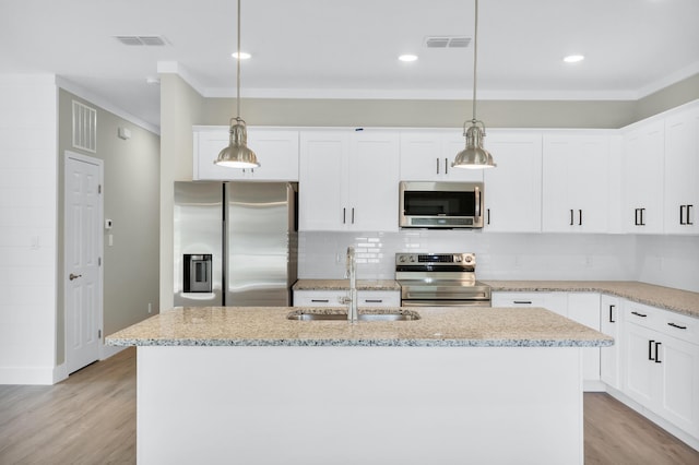 kitchen with sink, a kitchen island with sink, white cabinetry, stainless steel appliances, and decorative light fixtures