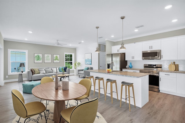 dining space with sink, light hardwood / wood-style flooring, and ornamental molding