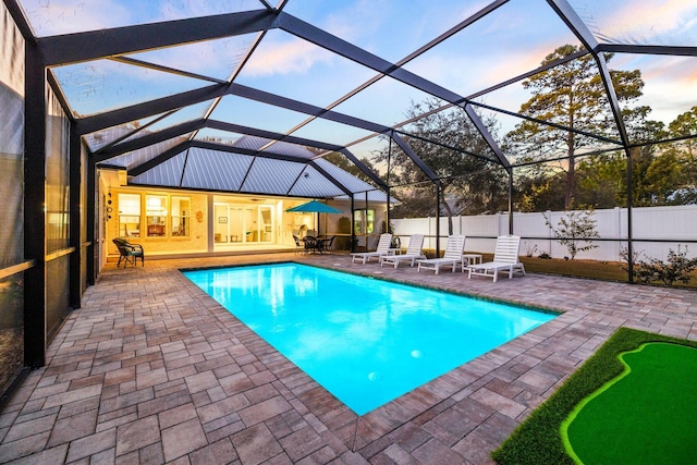 pool at dusk featuring a patio area and glass enclosure