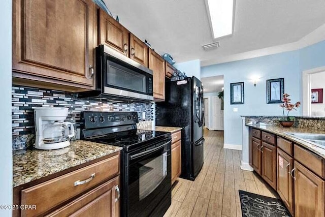 14825 Front Beach Rd Unit 2001, Panama City Beach, FL 32413 - kitchen with black appliances, sink, backsplash, light stone counters, and light hardwood / wood-style flooring