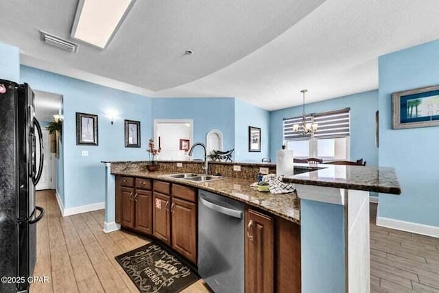 14825 Front Beach Rd Unit 2001, Panama City Beach, FL 32413 - kitchen with dark stone counters, sink, black fridge, a kitchen island with sink, and stainless steel dishwasher