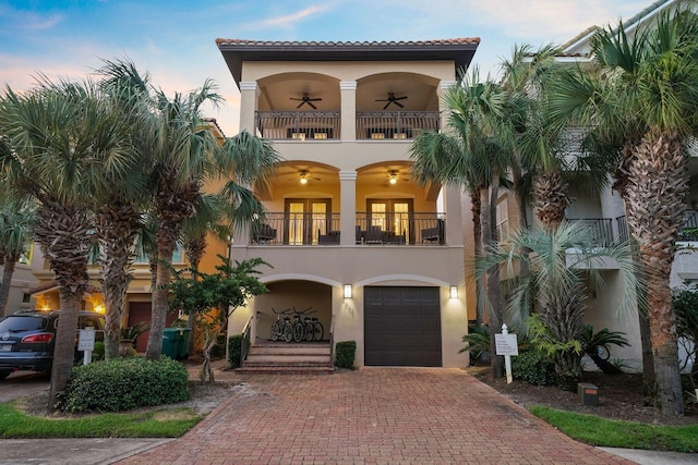 mediterranean / spanish-style house with ceiling fan, a balcony, a garage, and french doors