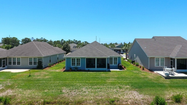 back of property featuring a patio area, a sunroom, and a lawn