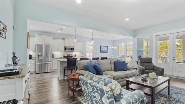 living room featuring french doors, a healthy amount of sunlight, dark hardwood / wood-style flooring, and a notable chandelier