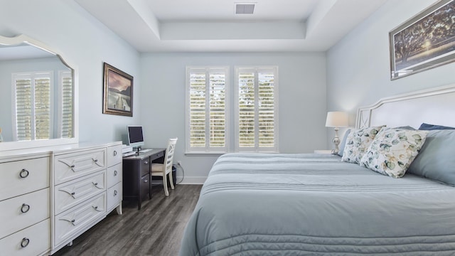 bedroom with dark wood-type flooring and a tray ceiling