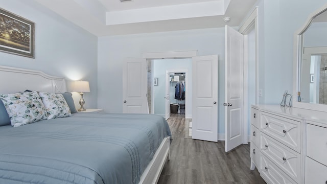 bedroom with a walk in closet, dark wood-type flooring, and a closet