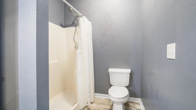 bathroom featuring toilet and curtained shower