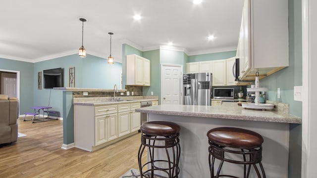 kitchen with decorative light fixtures, stainless steel appliances, kitchen peninsula, and a breakfast bar