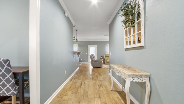 corridor with ornamental molding and light hardwood / wood-style flooring