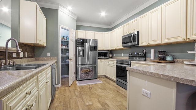 kitchen with sink, stainless steel appliances, ornamental molding, cream cabinetry, and light wood-type flooring