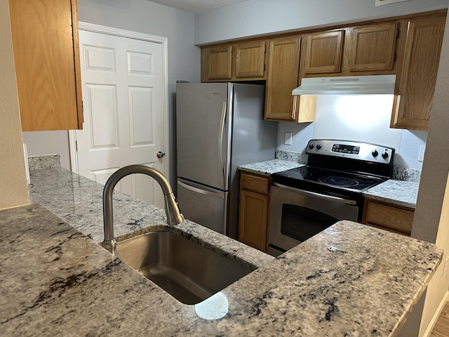 kitchen featuring stainless steel appliances, light stone counters, and sink