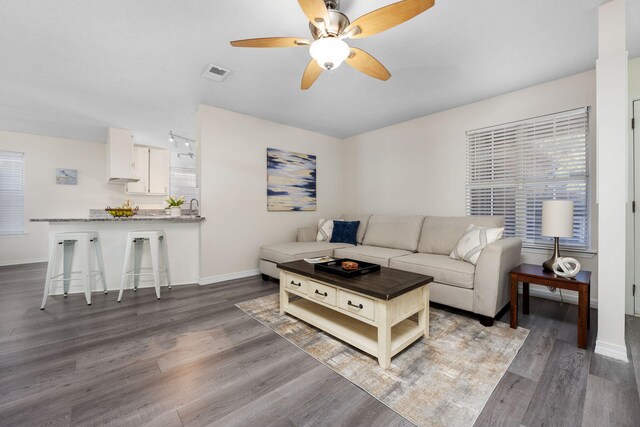 living area featuring baseboards, visible vents, ceiling fan, and wood finished floors