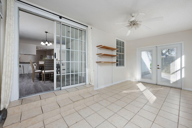 interior space featuring french doors, a textured ceiling, baseboards, and ceiling fan with notable chandelier