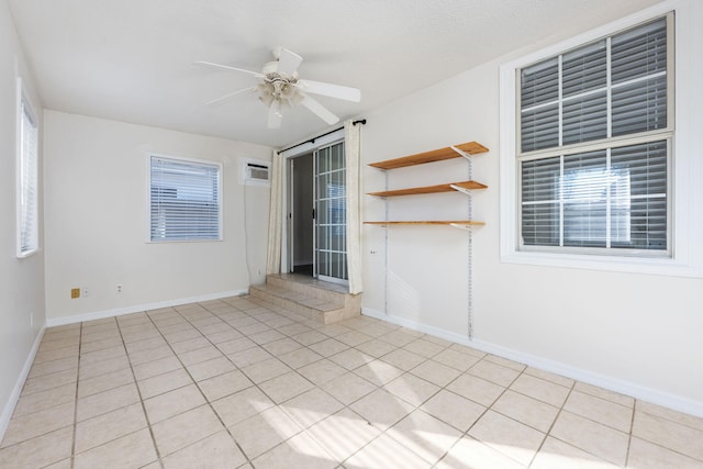 empty room with ceiling fan, light tile patterned floors, and baseboards