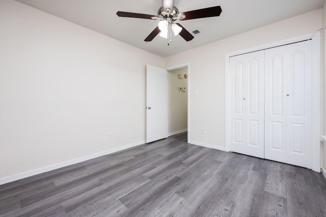 unfurnished bedroom featuring wood finished floors, a ceiling fan, visible vents, baseboards, and a closet