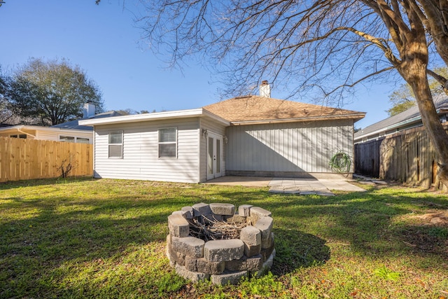 rear view of property featuring an outdoor fire pit, a fenced backyard, and a chimney