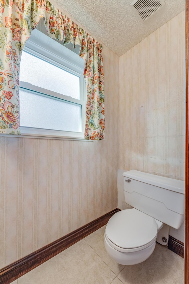 bathroom with toilet, tile patterned flooring, and a textured ceiling