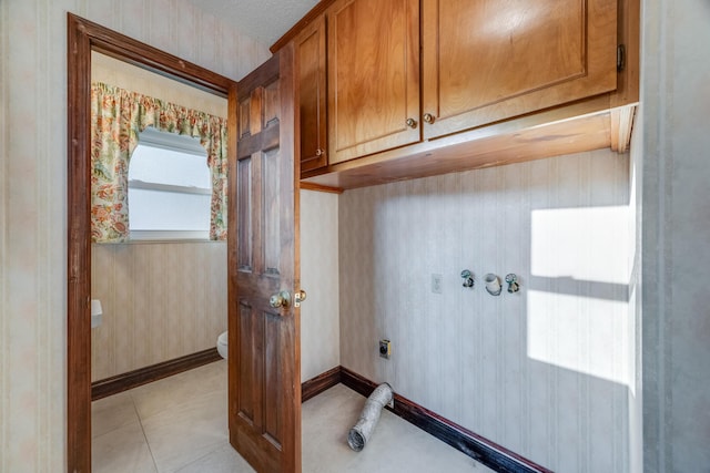 laundry room with cabinets, a textured ceiling, light tile patterned floors, and hookup for an electric dryer