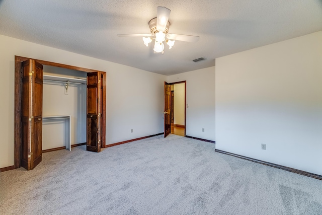 unfurnished bedroom with ceiling fan, light colored carpet, a closet, and a textured ceiling