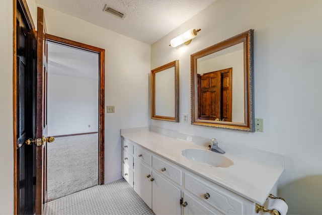 bathroom with a textured ceiling, vanity, and tile patterned flooring