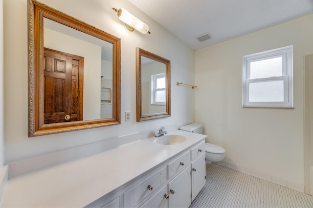 bathroom with tile patterned floors, vanity, toilet, and a healthy amount of sunlight