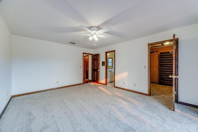 unfurnished bedroom featuring ceiling fan, connected bathroom, carpet flooring, a closet, and a walk in closet