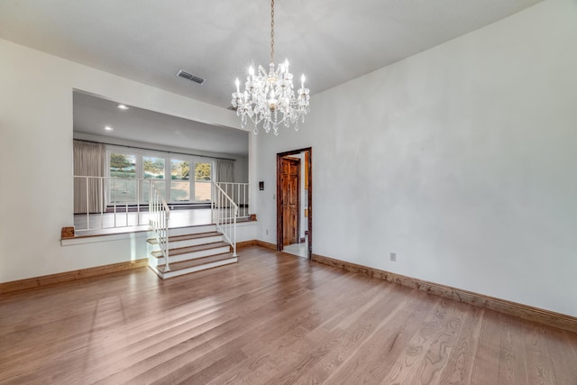 spare room featuring a chandelier and wood-type flooring