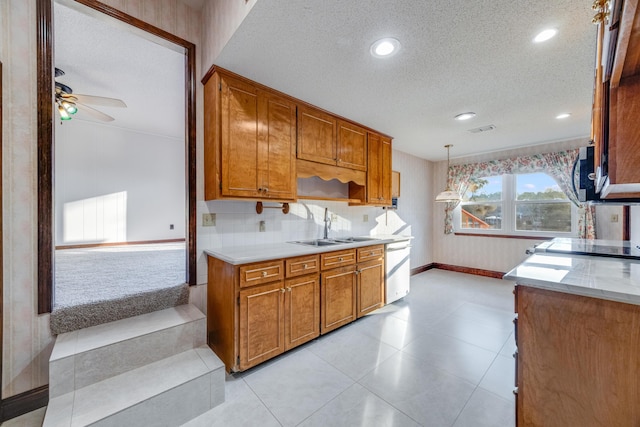 kitchen with ceiling fan, decorative backsplash, a textured ceiling, pendant lighting, and sink