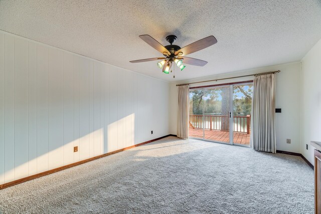 carpeted empty room featuring ceiling fan, a textured ceiling, and wooden walls