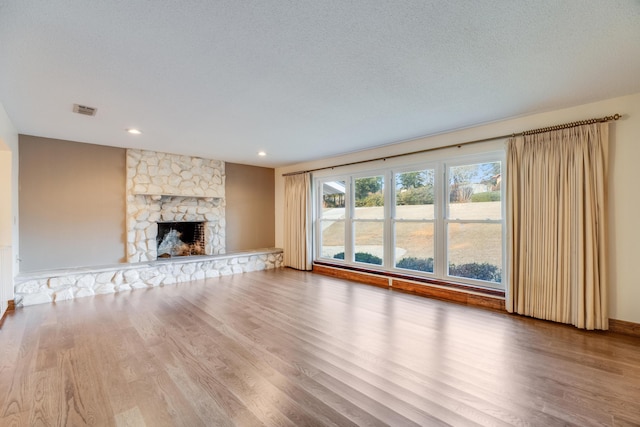 unfurnished living room with a textured ceiling, a fireplace, and hardwood / wood-style floors