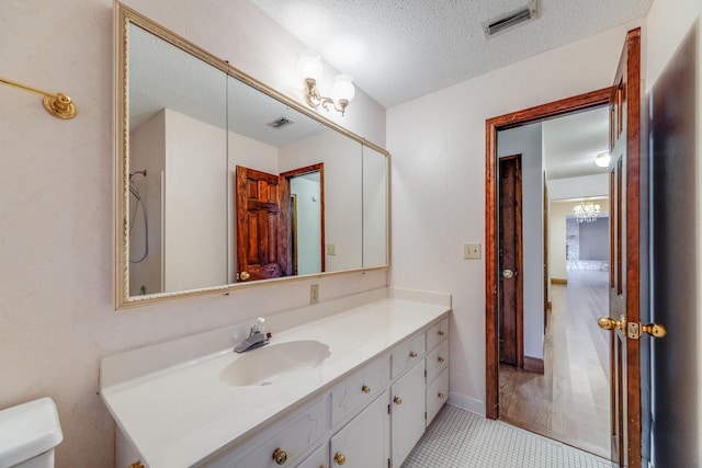 bathroom featuring toilet, vanity, tile patterned floors, and a textured ceiling