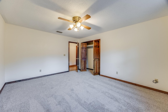 unfurnished bedroom with a textured ceiling, ceiling fan, a closet, and light colored carpet