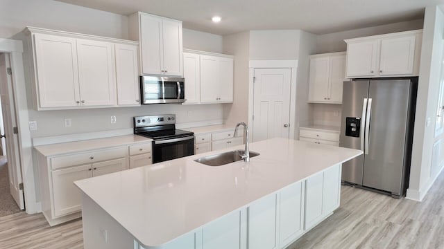 kitchen featuring a sink, stainless steel appliances, an island with sink, and white cabinets