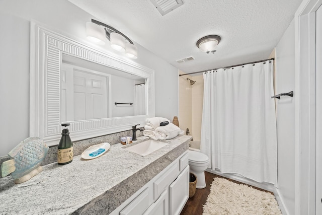 full bathroom with hardwood / wood-style floors, vanity, a textured ceiling, shower / tub combo, and toilet