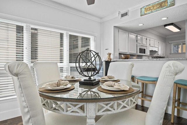 dining space with ornamental molding, dark wood-type flooring, and ceiling fan