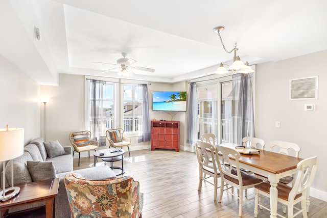 living room featuring light hardwood / wood-style floors, a tray ceiling, and ceiling fan