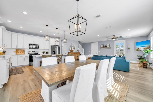 dining room featuring light wood-type flooring and ceiling fan with notable chandelier