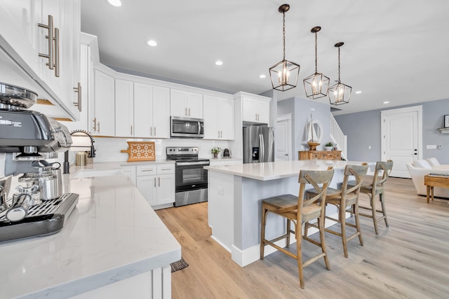 kitchen with white cabinets, a center island, stainless steel appliances, sink, and hanging light fixtures