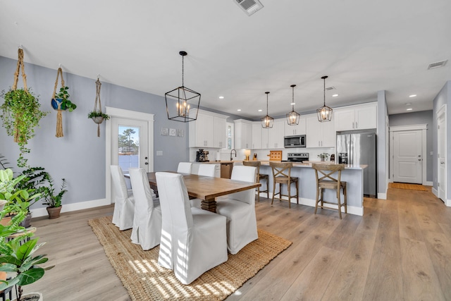 dining space featuring a notable chandelier, light hardwood / wood-style floors, and sink