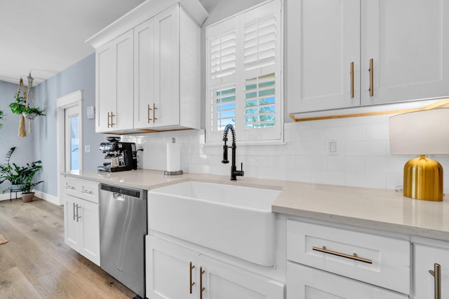 kitchen featuring stainless steel dishwasher, sink, light wood-type flooring, white cabinetry, and light stone countertops