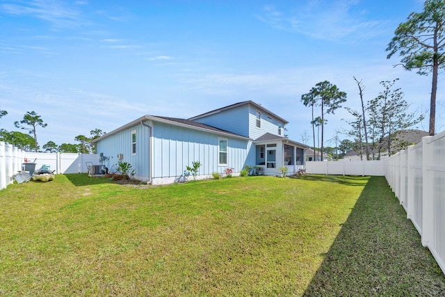 rear view of property with central AC, a yard, and a sunroom