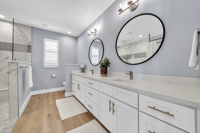 bathroom featuring vanity, toilet, a tile shower, and wood-type flooring