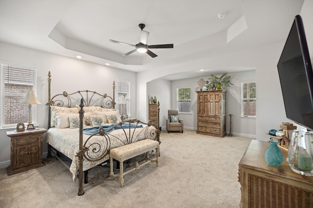 carpeted bedroom featuring ceiling fan and a tray ceiling