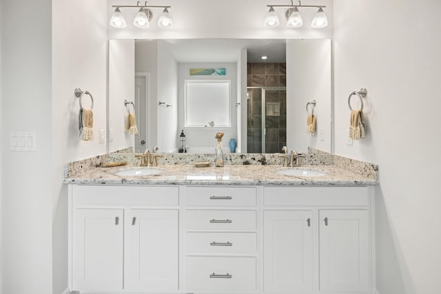 bathroom featuring a shower with shower door and vanity