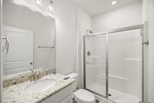 bathroom featuring toilet, a shower with door, and vanity