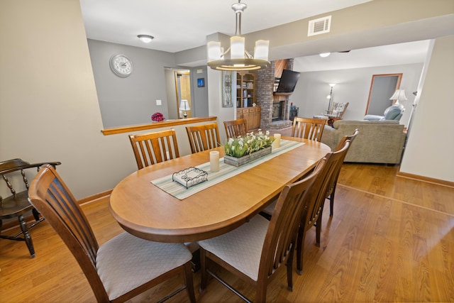 dining space featuring a fireplace and light hardwood / wood-style flooring