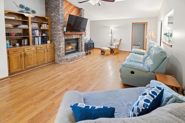 living room with light hardwood / wood-style flooring, a fireplace, vaulted ceiling, and ceiling fan